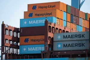 Stacked hapag-lloyd and maersk shipping containers on a cargo ship